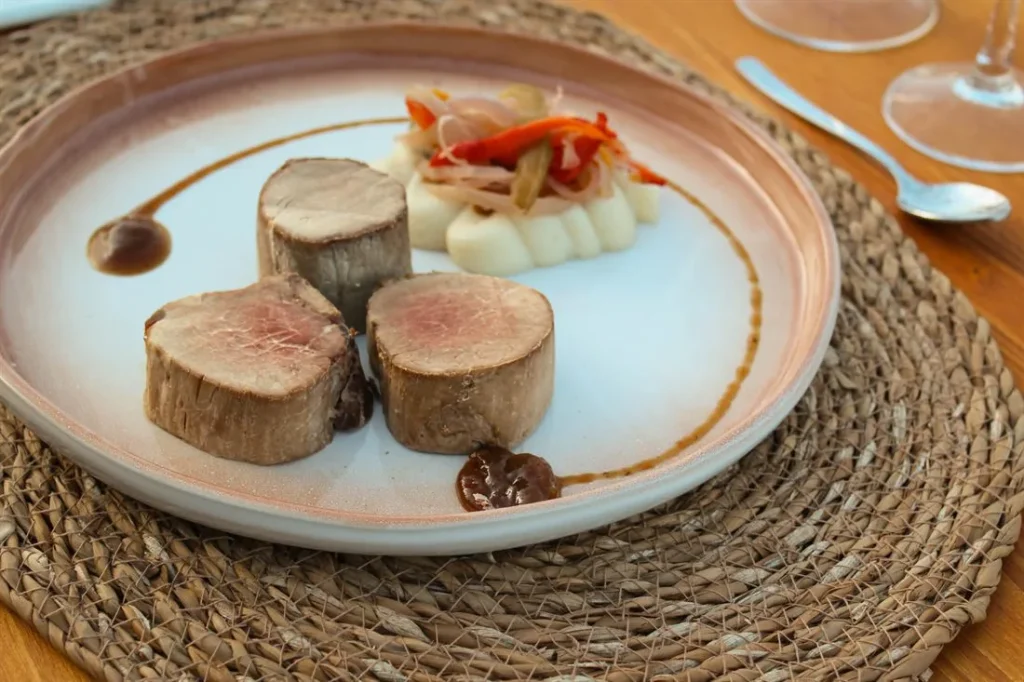 Meat dish with side dishes served on handmade ceramic plates